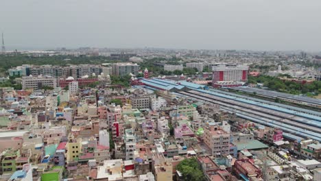 aerial drone shot of chennai central railway station and suburban terminal with crowded residentials buildings in chennai, tamil nadu. daytime front pull shot.