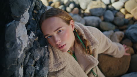 coast girl posing rocks on beach closeup. serene beautiful woman with braids