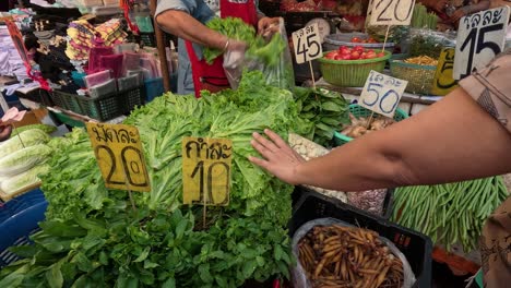 customers buying vegetables at a busy market stall