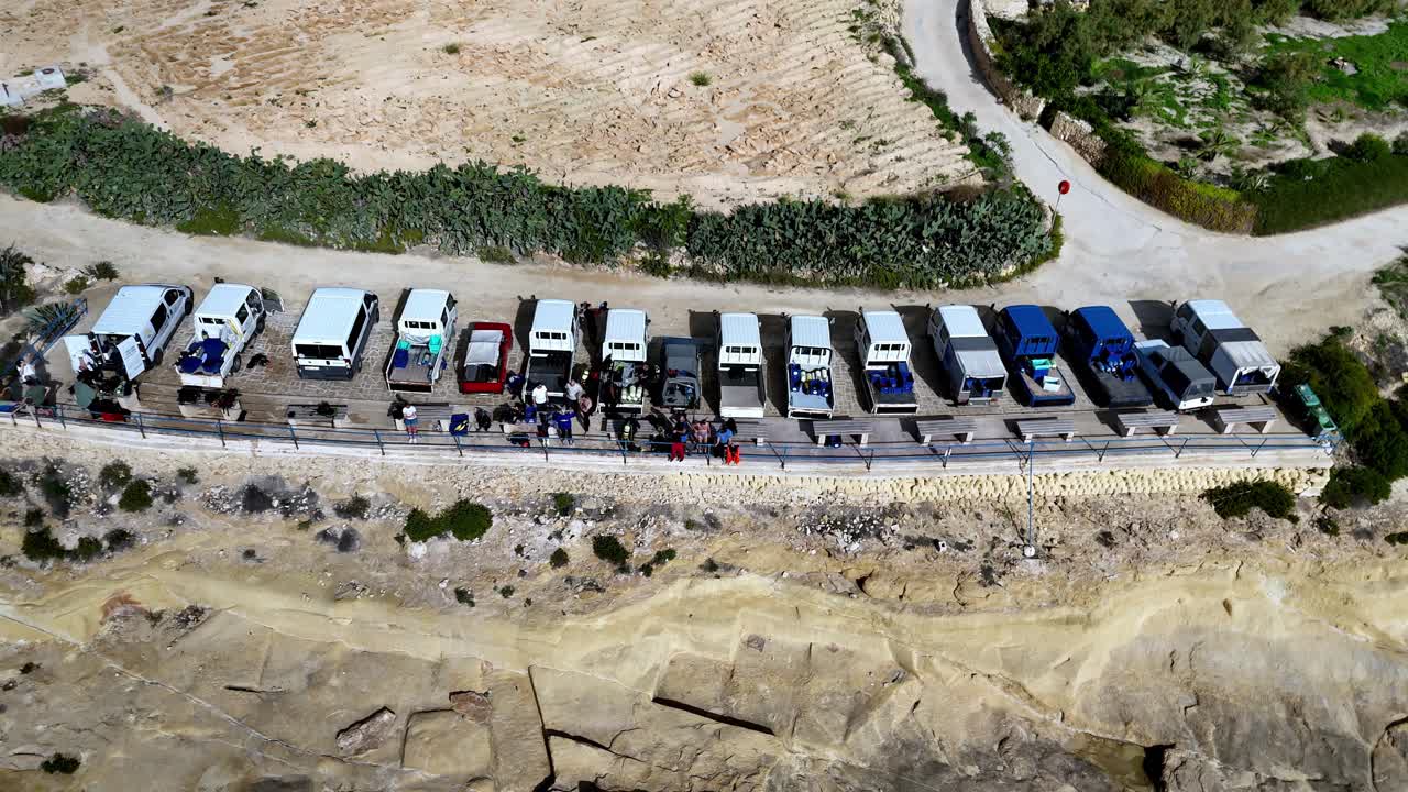 High Angle Aerial View of Local Salt Pan Workers Parking White Vans and Trucks along Sandy Coastal Roadside under Bright Summer Sun Featuring Warm Earthy Tones and Scenic Arid Mediterranean Landscape