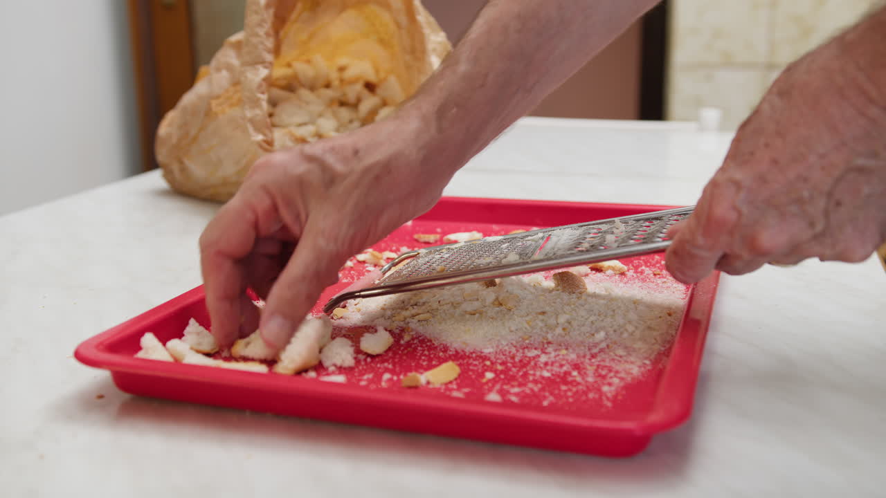 Mani che grattugiano il pane per fare pangrattato