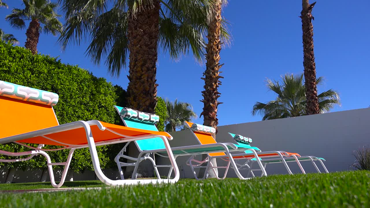 coloridas sillas de jardín se sientan alrededor de una piscina en una casa de palm springs 1
