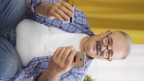 Vertical-video-of-Old-man-shopping-on-the-phone.