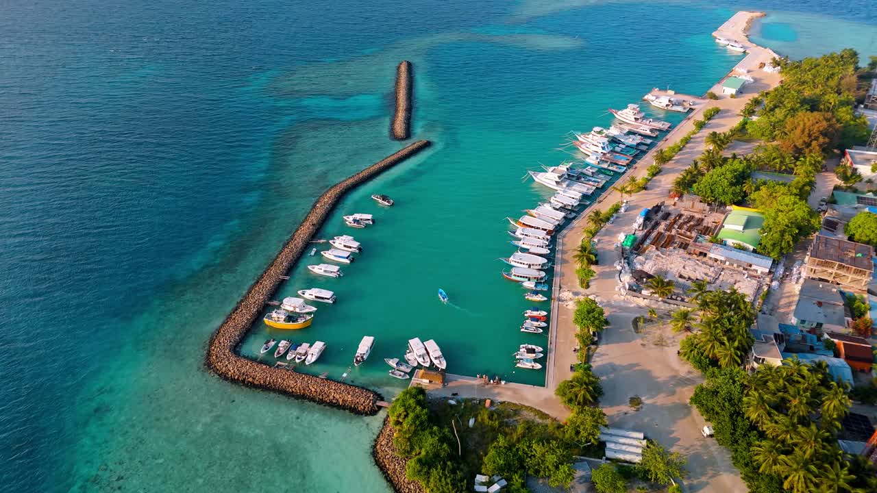 A stunning aerial drone view showcasing Rasdhoo Island surrounded by crystal-clear turquoise waters and vibrant coral reefs in the Maldives.