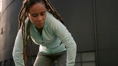 vista frontal de una joven mujer afroamericana descansando después de hacer ejercicio en la ciudad 4k