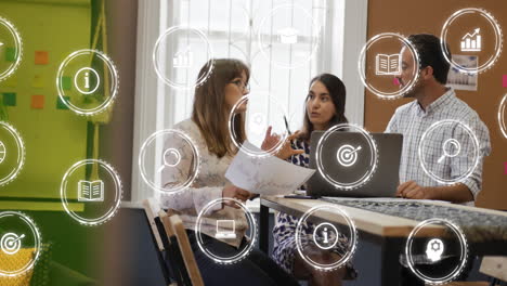 Animation-of-multiple-digital-icons-against-diverse-colleagues-discussing-together-at-office