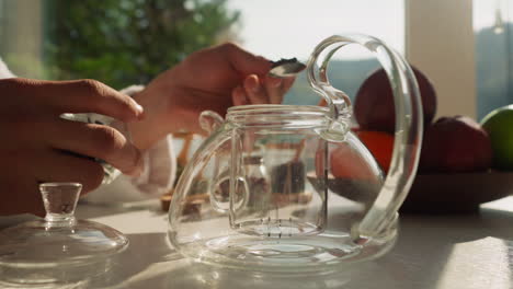 husband pours dried tea mix into teapot. caring boyfriend makes tea for beloved family for breakfast on vacation. tea accessories for ceremony