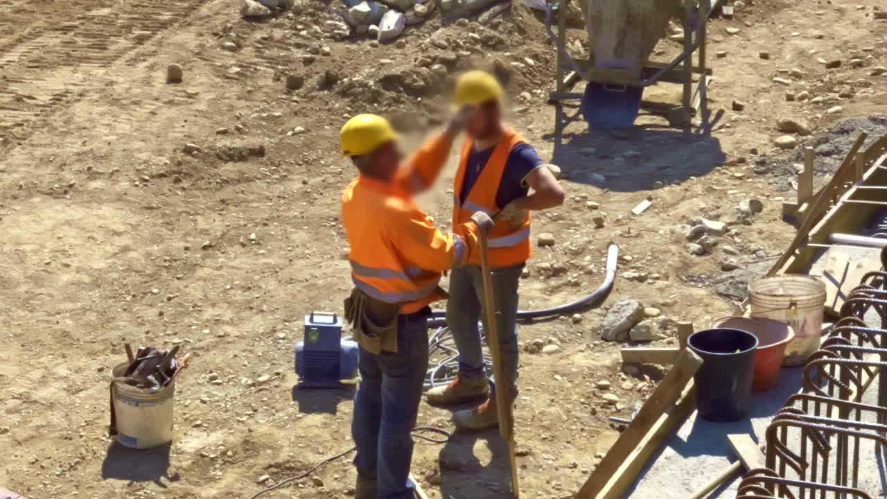 dos trabajadores de cuello azul hablando en el sitio de construcción