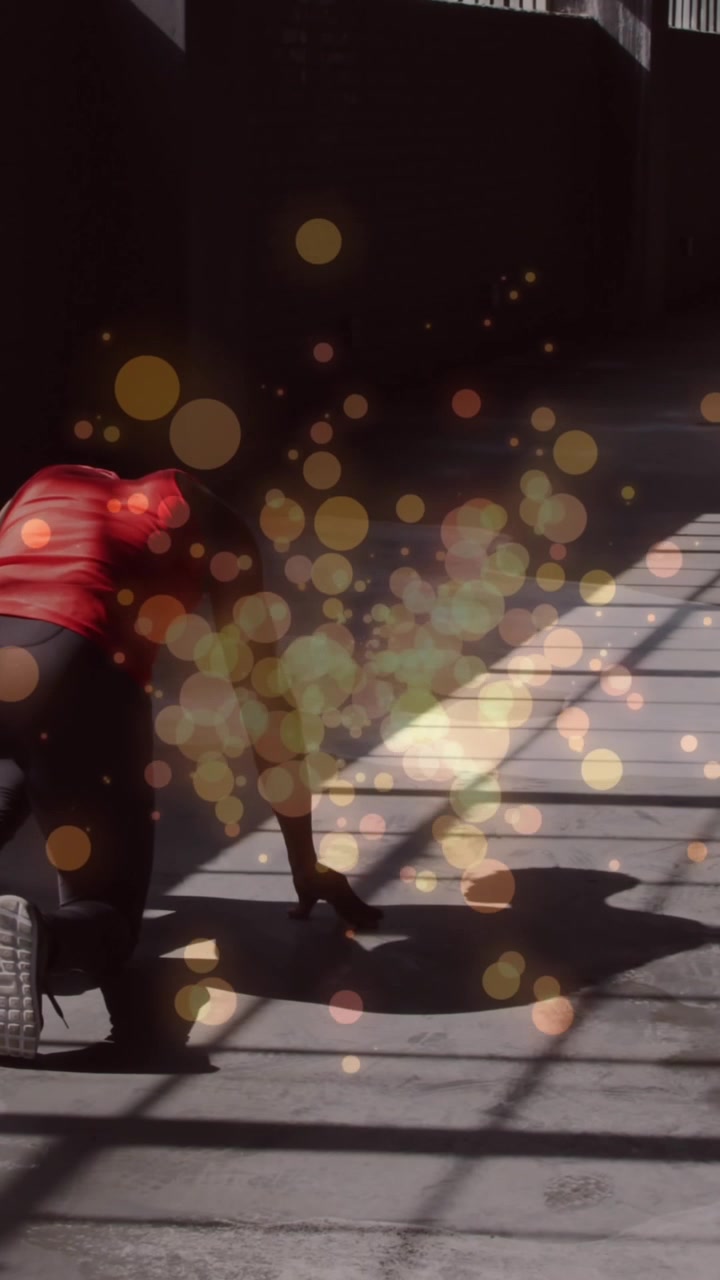 Orange spots of lights against rear view of african american woman in start position ready to run