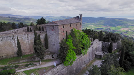 Fortress-of-Girifalco-on-hill-in-rural-Tuscany,-forward-rising-aerial