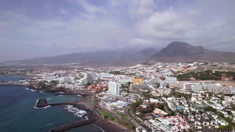 aerial tilt up reveal of a touristic resort city on tenerife coastline