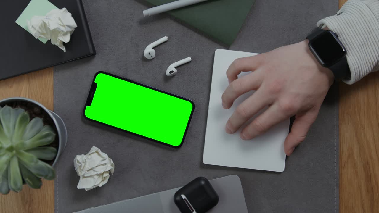 la mano de un hombre se encuentra en un cuaderno, al lado de un teléfono móvil con pantalla verde