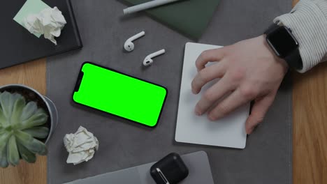la mano de un hombre se encuentra en un cuaderno, al lado de un teléfono móvil con pantalla verde
