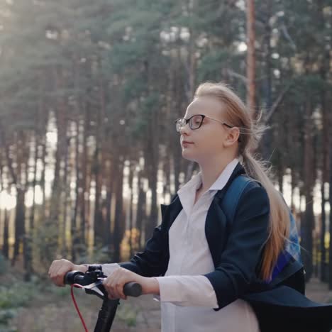 A-girl-in-school-uniform-rides-an-electric-scooter-through-the-park-1