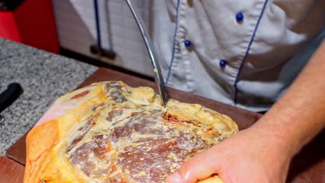 imágenes de cerca del cocinero preparando un prosciutto.