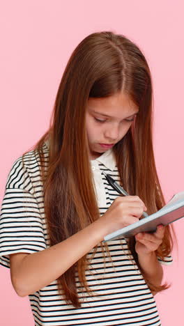 child girl kid thoughtfully writing notes in notebook diary carefully planning detailed todo list