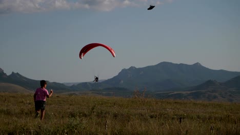 a boy with a plane in his hands runs against the background of mountains