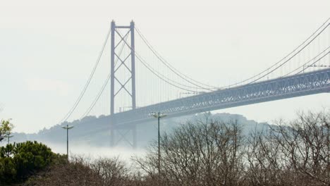 famoso puente suspendido de lisboa sobre un río tranquilo en tiempo de niebla, portugal