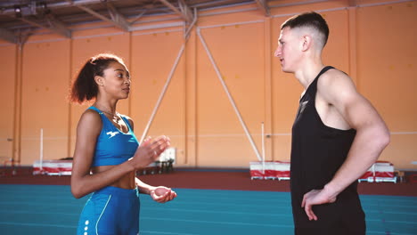 young sportswoman and sportsman talking together in an indoor sport facility during training session