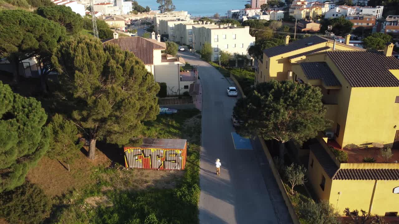 вид с дрона на улице льянсы, человек и машина проезжают по маленькой улице льянсы, небольшого городка в эмпорде, каталония, испания