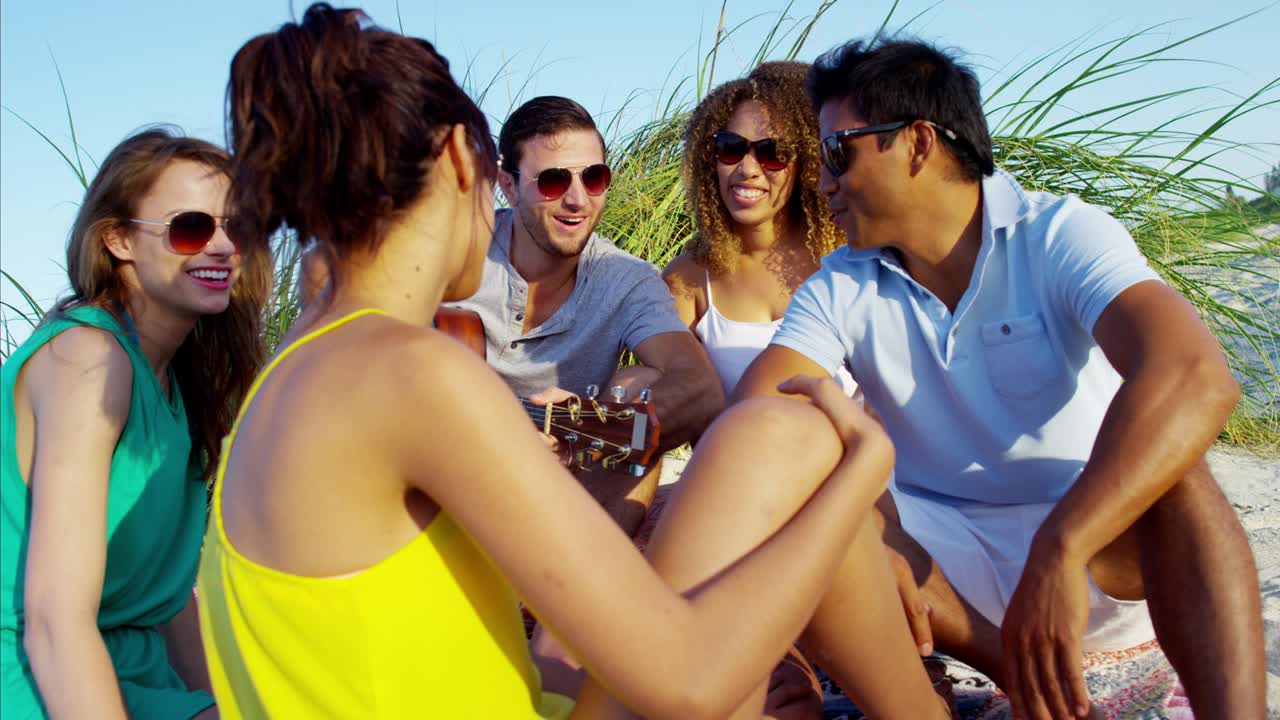 Amici multietnici con la chitarra in vacanza al mare