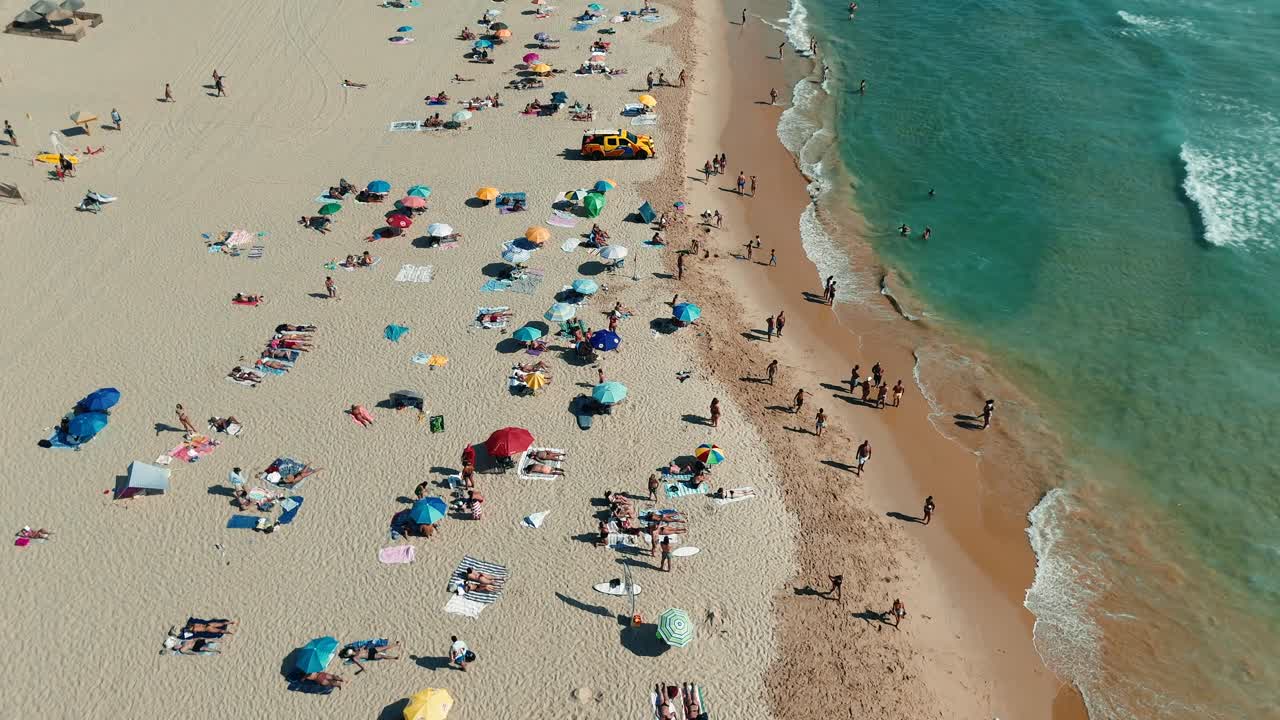 Aerial view of a crowded beach with people enjoying the summer sun