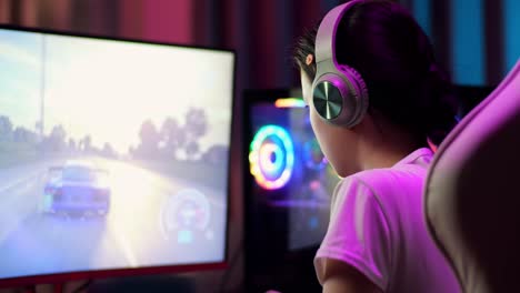 primer plano de una adolescente asiática emocionada que celebra la victoria y baila mientras juega videojuegos en la computadora, jugando un videojuego de carreras