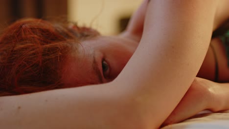 dreamy view of a stunning redheaded woman lying in bed and looking at the viewer