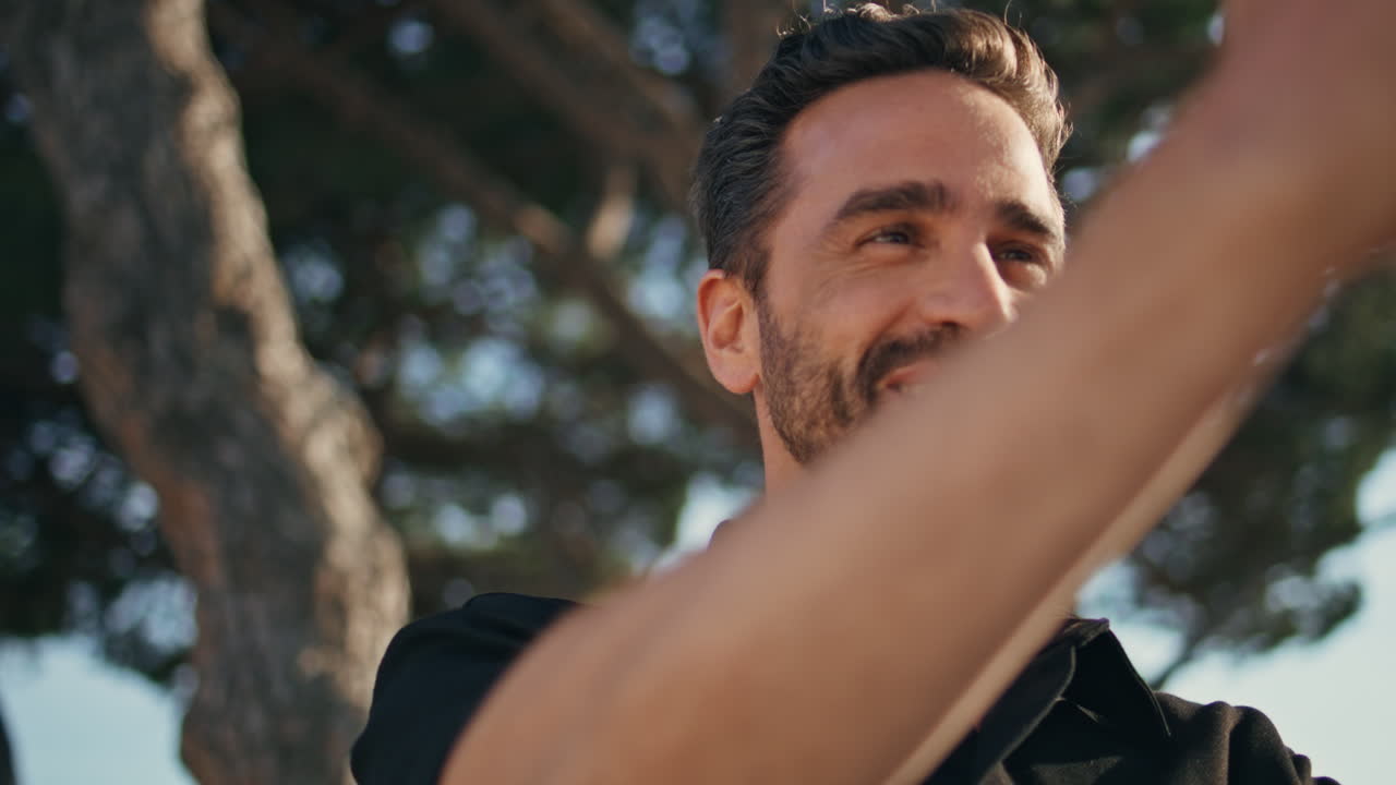 나무 배경에서 휴대전화로 전화하는 즐거운 관광 비디오 클로즈업.