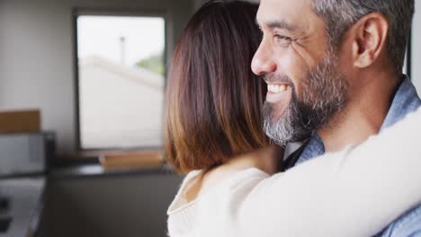 pareja feliz diversa vestida con ropa casual abrazándose juntos en la cocina