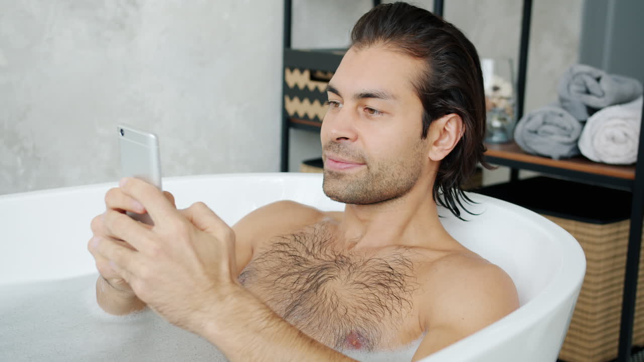 Man Relaxing in a Bath with a Phone