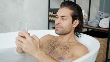 man relaxing in a bath with a phone