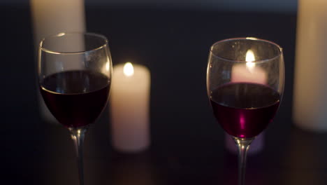 dos copas de vino tinto en una mesa iluminada con velas - dolly a la derecha