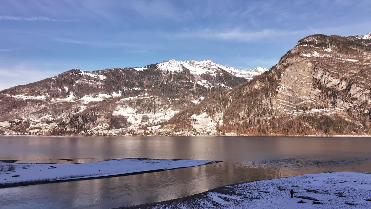 A picturesque winter scene at Lake Walensee, Switzerland, where calm waters reflect snow-capped mountains and the surrounding landscape, creating a serene and tranquil atmosphere.