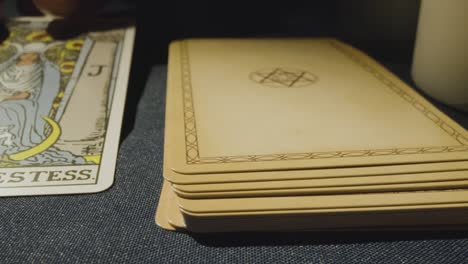 disparo de cerca de una persona que da la lectura de la carta del tarot colocando la carta de la alta sacerdotisa en la mesa