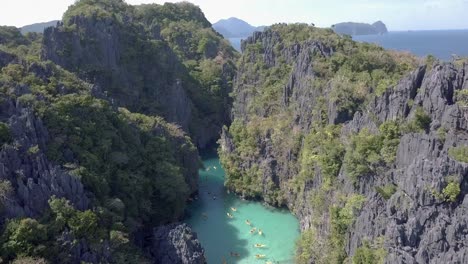 4K-Luftdrohnenansicht-Von-Menschen,-Die-An-Einem-Sonnigen-Tag-In-Einer-Kleinen-Lagune-Um-Die-Miniloc-Insel-In-El-Nido,-Palawan,-Philippinen-Kajak-Fahren