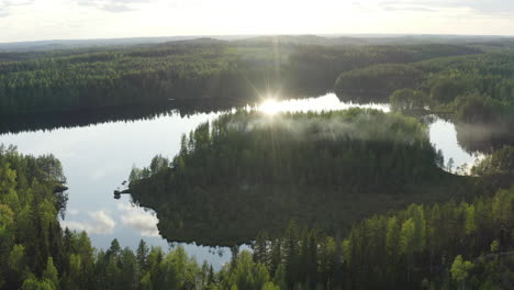 aerial drone shot of beautiful summer lake scenery with smoke floating from sauna in the woods