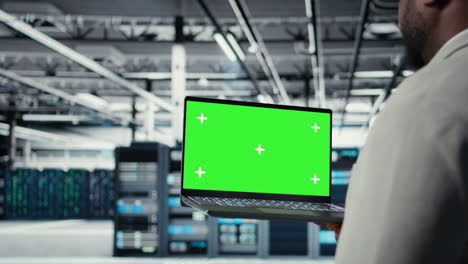 close up of technician using green screen laptop in data center