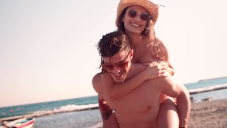 young woman at the beach piggy backing on boyfriend