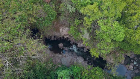 Luftaufnahme-Einer-Drohne,-Die-Von-Einem-Kleinen,-Von-Bäumen-Umgebenen-Fluss-Wegfliegt