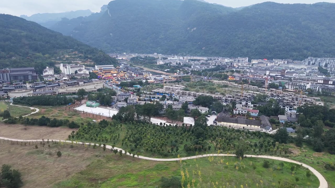 Góc nhìn tiến về phía vùng ngoại ô dân cư hướng tới trung tâm thị trấn Trương Gia Giới, những khu nhà mới nhường chỗ cho các công trình kiến trúc tinh xảo với những ngọn núi đá karst phủ rừng phía sau, Trương Gia Giới, Hồ Nam, Trung Quốc
