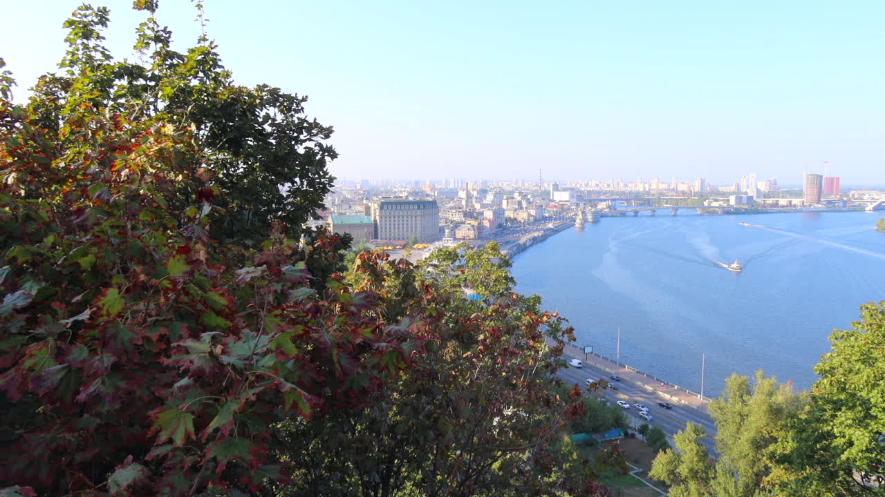 hermosa vista desde el puente de vidrio en el famoso río dnipro en la ciudad de kiev, ucrania, edificios y árboles en un día soleado, toma de 4k