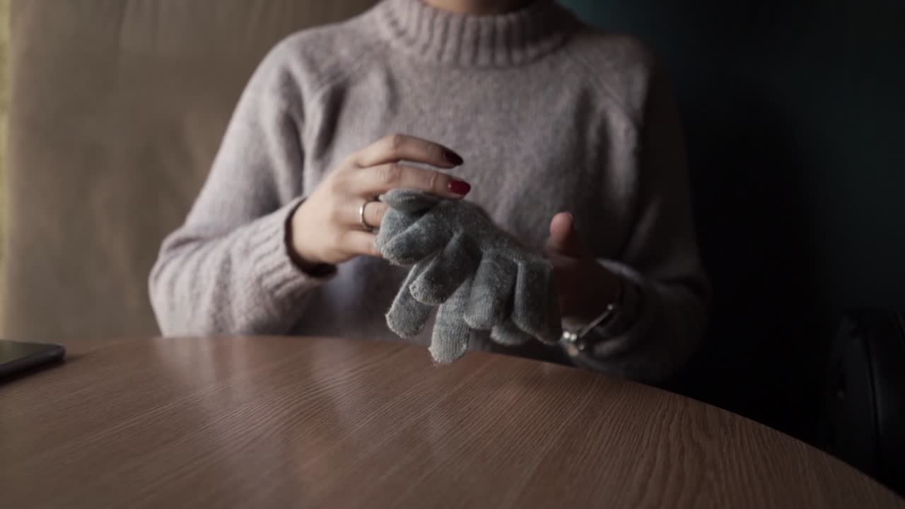 Gray winter gloves on the table. And the girl who holds them.