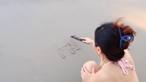 persona escribiendo 'hola' en la arena