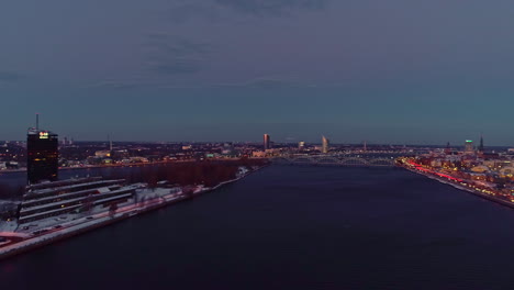 Weitwinkelaufnahme-Aus-Der-Luft,-Die-Den-Fluss-Daugava-In-Der-Stadt-Riga-Nach-Sonnenuntergang-Zeigt---Lettland,-Europa