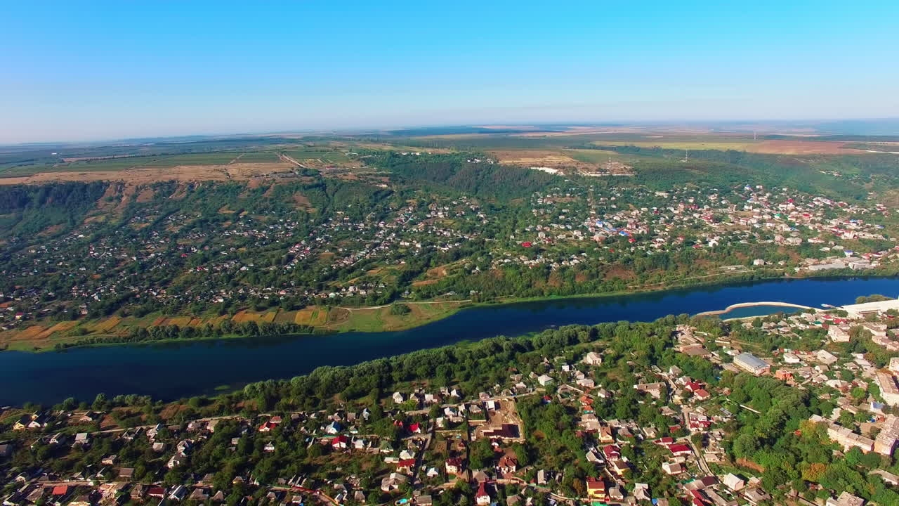 Scenery of the city built on the both banks of the beautiful river. Amazing view of the landscape on sunny summer day from air.