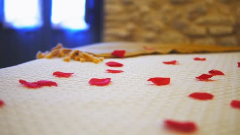 Close-up-of-clean-hotel-bedroom-with-rose-petals-on-the-bed,-romantic-concept