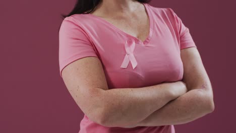 woman with arms crossed wearing pink breast cancer awareness ribbon on t-shirt