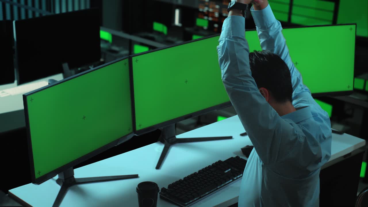 지친 아시아인 남자가 사무실에서 여러 컴퓨터 모니터를 모의로 작업하는 동안 스트레칭하는 측면 시각