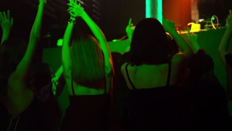 grupo de personas bailando en un club nocturno de discoteca al ritmo de la música de dj en el escenario